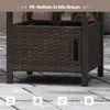 Close-up of the base of an outdoor table made of woven brown rattan, with metal legs, placed on a paved patio. Podgląd zdjęcia produktu