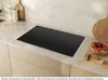 A modern kitchen countertop with an induction cooktop, a bowl of dried fruit, and kitchen utensils. Voir les images du produit