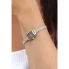A close-up shot of a woman's arm wearing a gold Daniel Wellington watch with a black face. Voir les images du produit