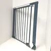 A gray metal safety gate is shown standing upright in a corner against a white wall. Voir les images du produit