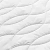 A close-up view of a white quilted fabric surface, showing the texture and stitching pattern. Produktbild-Vorschau
