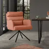 An orange armchair with a black metal base is placed in a modern dining room setting next to a dark wood table with a green cup on it.