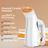 A white handheld garment steamer is shown with stacked folded clothes in the background. Text overlays describe its features. Podgląd zdjęcia produktu