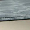 A close-up view of the edge of a rug with a wavy pattern. Produktbild-Vorschau