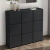 A black shoe cabinet with nine compartments is shown in a room with a mirror and a plant. Produktbild-Vorschau