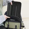 A person is putting a black laptop case into a backpack. Produktbild-Vorschau