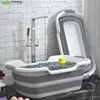 A collapsible bathtub filled with water and a rubber duck, next to a shower faucet. Voir les images du produit