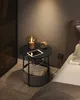 A nightstand with a lamp, tablet, and small fan next to a bed. Náhled obrázku produktu