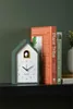 A cuckoo clock and two books are placed on a shelf against a dark green wall. Náhľad obrázku produktu