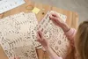 A person's hands are holding and examining wooden puzzle pieces on a wooden table. Podgląd zdjęcia produktu