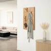 A wooden coat rack with a gray robe and a brown purse hanging on it, mounted on a white wall. In the background, a sofa and a coffee table are visible. Produktbild-Vorschau