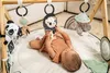 A baby is lying on a play mat and interacting with a baby gym. Produktbild-Vorschau