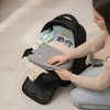 A person is packing a black backpack with clothes and travel accessories. Produktbild-Vorschau