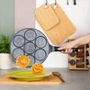 A hand holding a smiley face pancake pan over a plate with two smiley face pancakes. Náhled obrázku produktu