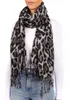 A woman wearing a white long-sleeved shirt and blue jeans is modeling a leopard-print scarf. Produktbild-Vorschau
