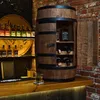 A wooden barrel-shaped wine cabinet with bottles and a glass of whiskey on a bar counter. Produktbild-Vorschau