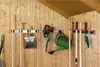 Garden tools are neatly organized on a wall-mounted rack in a wooden shed. Anteprima dell’immagine prodotto