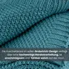 A close-up view of a teal knitted blanket, folded to show its texture and weave. Text overlay describes its features. Náhled obrázku produktu