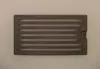 A rectangular cast iron grate with horizontal slots, placed on a light gray background. Náhled obrázku produktu