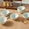 A set of six ceramic bowls is displayed on a wooden table, with three glass jars containing food items in the background. Produktbild-Vorschau
