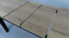 A close-up, angled view of a wooden table with black metal legs. Náhled obrázku produktu