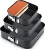 A stack of three black square springform pans, with the top pan containing a slice of tiramisu cake. Anteprima dell’immagine prodotto