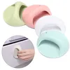 Four self-adhesive drawer pulls in different pastel colors are arranged in a diagonal line. A close-up inset shows a hand using one of the pulls on a drawer. Produktbild-Vorschau