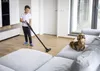 A boy is vacuuming the floor while a dog sits on the couch. Náhled obrázku produktu