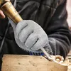 A person wearing protective gloves is carving wood with a chisel. Produktbild-Vorschau