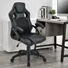 A black gaming chair is positioned in an office setting, next to a desk with a computer and books. Náhled obrázku produktu