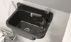 A black sink with a silver faucet mounted on a tiled wall, with a laundry basket in the foreground. Podgląd zdjęcia produktu