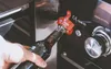 A hand is opening a bottle with a beer opener attached to a grill. Produktbild-Vorschau