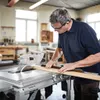 A man is using a table saw in a workshop. Podgląd zdjęcia produktu