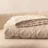A folded beige blanket with a cable knit pattern is placed on a matching textured surface, likely a sofa or chair. Anteprima dell’immagine prodotto