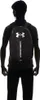 A person wearing a black shirt and black pants is shown from the back, wearing a black backpack with a silver Under Armour logo and text. Náhled obrázku produktu