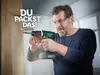A man is using a cordless drill to drill into a wooden beam. He is wearing safety glasses and earplugs. Sawdust is flying around the drill. Produktbild-Vorschau