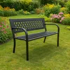 A black metal garden bench sits on a lush green lawn surrounded by colorful flowers and foliage. Anteprima dell’immagine prodotto