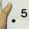 A close-up of a hand touching a fabric advent calendar with a number '5' and a star ornament printed on it. Podgląd zdjęcia produktu