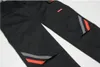 A close-up view of black work pants with reflective orange and gray stripes on the lower legs. Produktbild-Vorschau