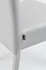 A close-up view of a light gray chair, focusing on a small black tag attached to the seam. Voir les images du produit