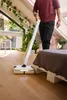 A person is using a floor cleaner in a room with a bed and plants. Anteprima dell’immagine prodotto