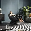 A woman is relaxing in a black massage chair in a modern living room. Produktbild-Vorschau