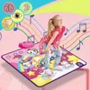 A young girl is dancing on a colorful unicorn-themed dance mat with musical notes and rainbows depicted on it. A pink music player is placed on the mat. Produktbild-Vorschau