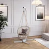 A hanging chair with a stand is set up in a well-decorated room with artwork and lighting. Podgląd zdjęcia produktu