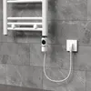 A close-up of a white electric towel rail with a digital thermostat, plugged into a white wall socket against a grey tiled wall. Produktbild-Vorschau