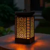 A solar lantern with a flame effect sits on an outdoor table at dusk. Podgląd zdjęcia produktu
