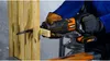 A person wearing gloves is using a reciprocating saw to cut a wooden post with a nail sticking out of it. Voir les images du produit