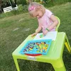 A young girl is playing with colorful mosaic pieces on a table outdoors. Náhľad obrázku produktu