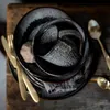 A close-up view of stacked ceramic dishes and a mug on a wooden surface. Anteprima dell’immagine prodotto