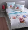 A bed with beach-themed bedding, including a duvet cover and pillows, set in a bedroom. Produktbild-Vorschau